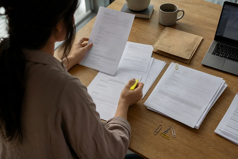 Analyst sorting printed dispute notices, an invoice and a delivery receipt into an evidence pile