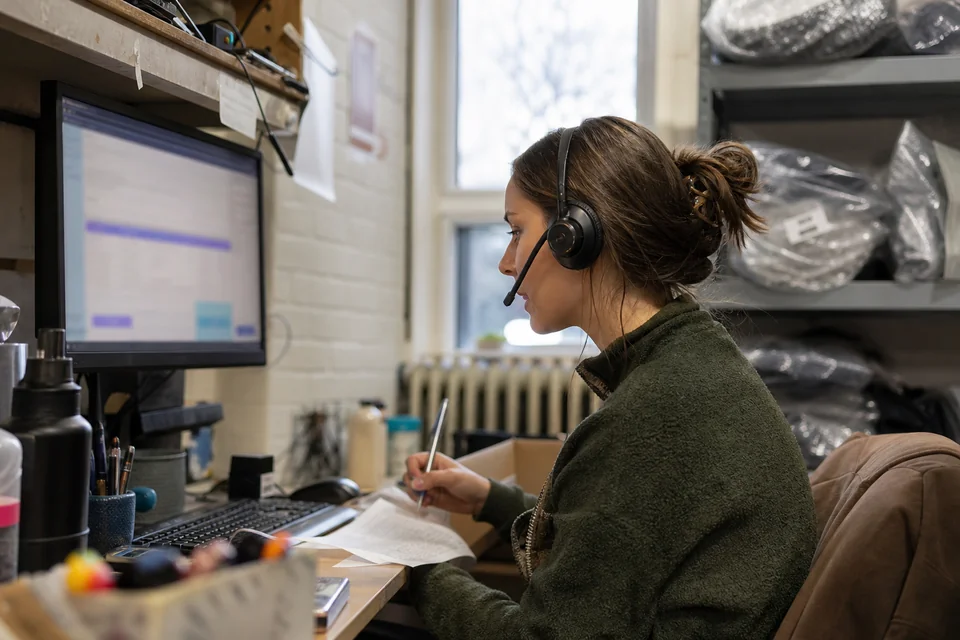 Support agent of an online store on a call checking an order slip in the back room of the shop