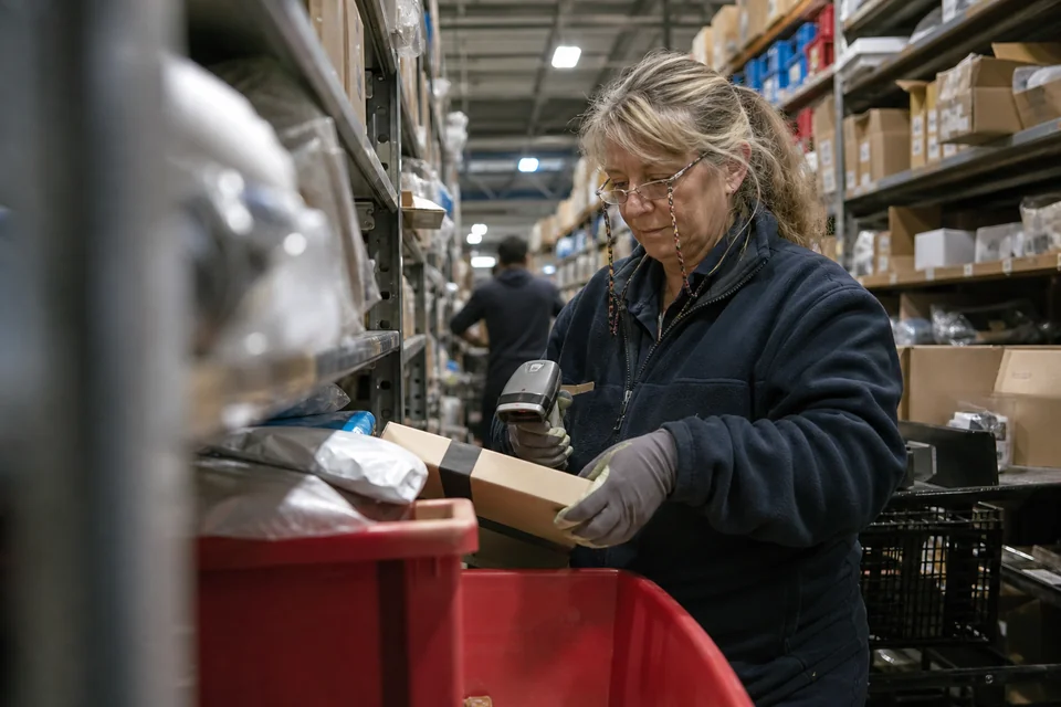 Fulfillment worker scanning a flagged parcel between warehouse racks
