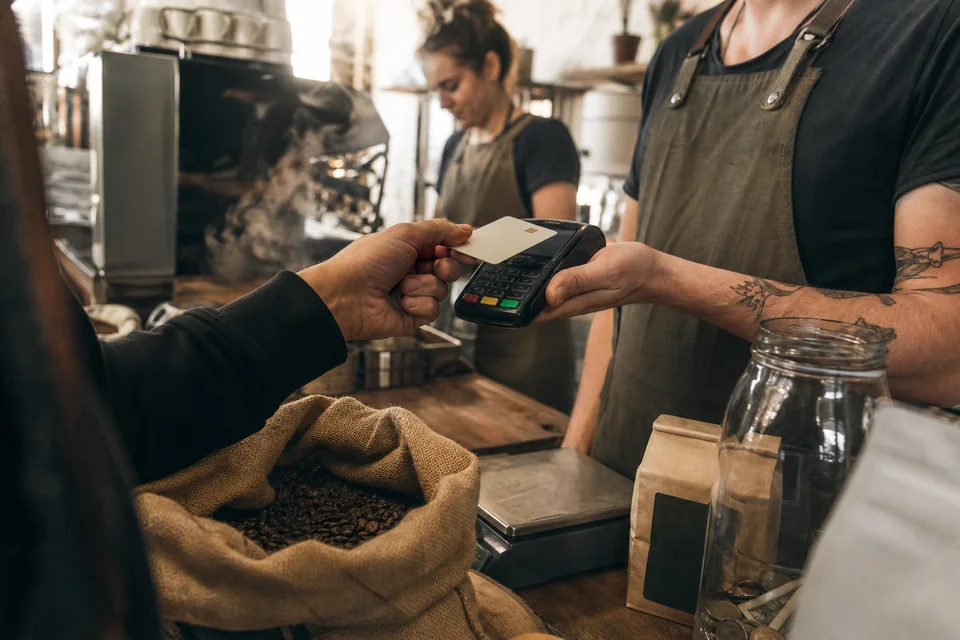 Customer tapping a contactless card on a payment terminal at a coffee roastery counter
